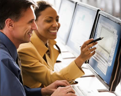 Photo shows two employees looking at a computer screen.